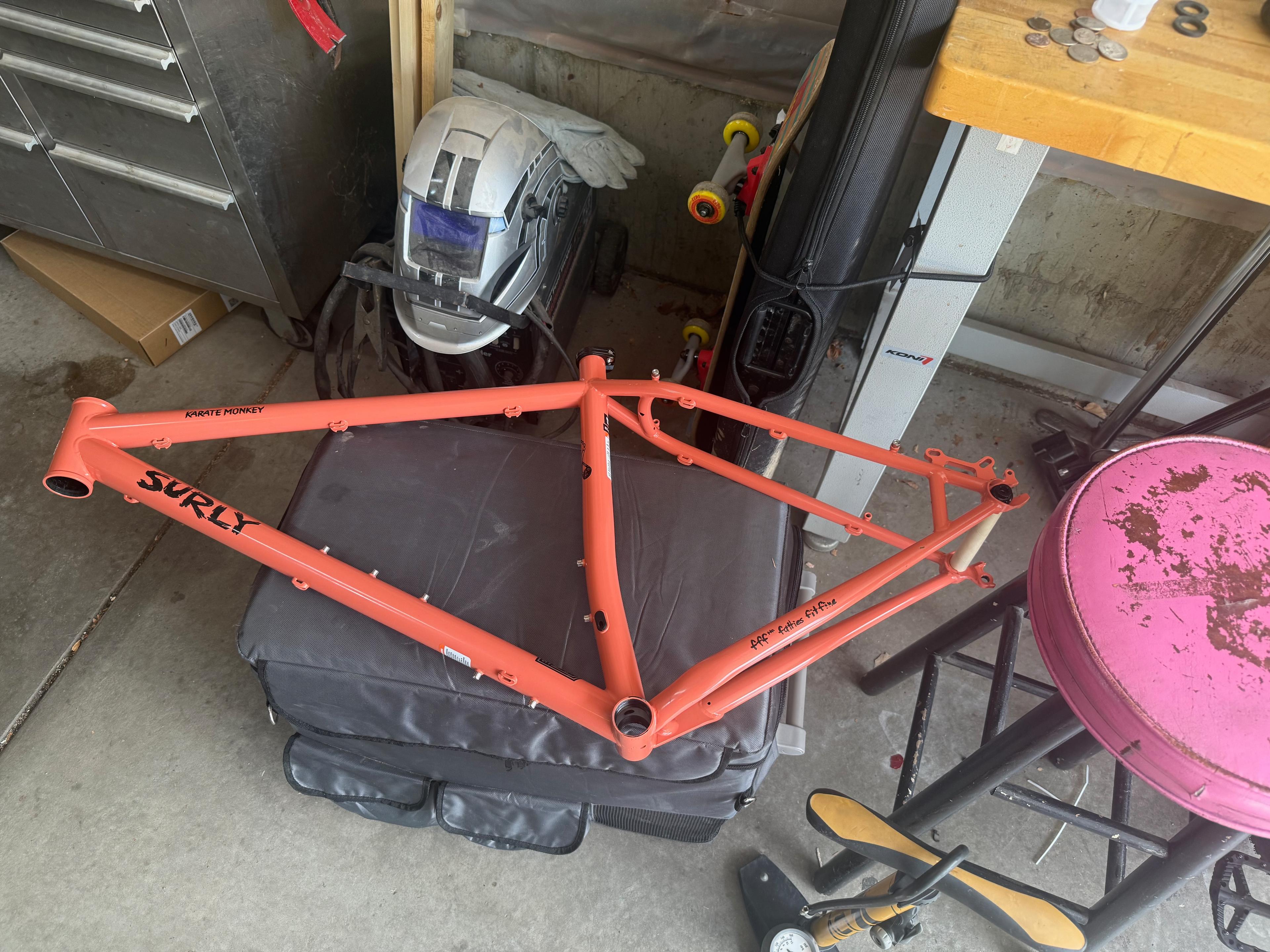 Bare orange Surly Karate Monkey frame sitting in a garage before the build