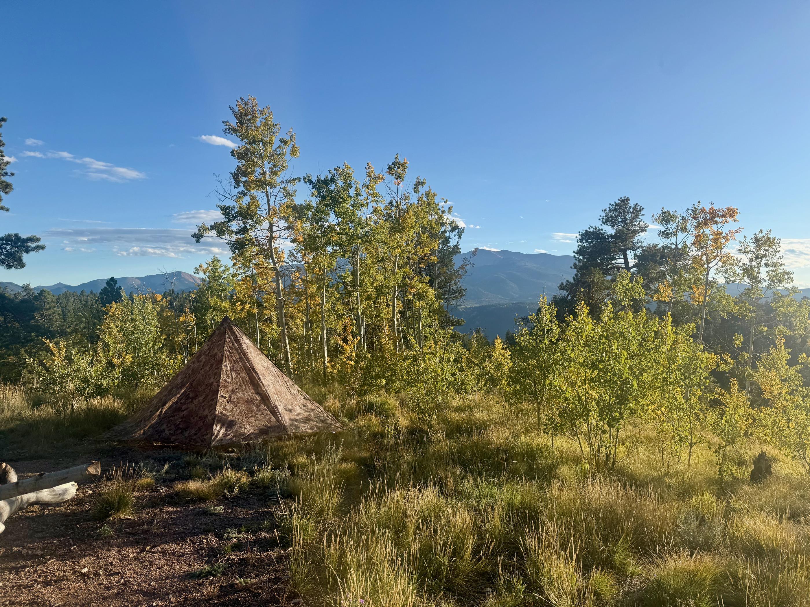 A pyramid tent at dusk with a pastel pink and blue sky over silhouetted mountains