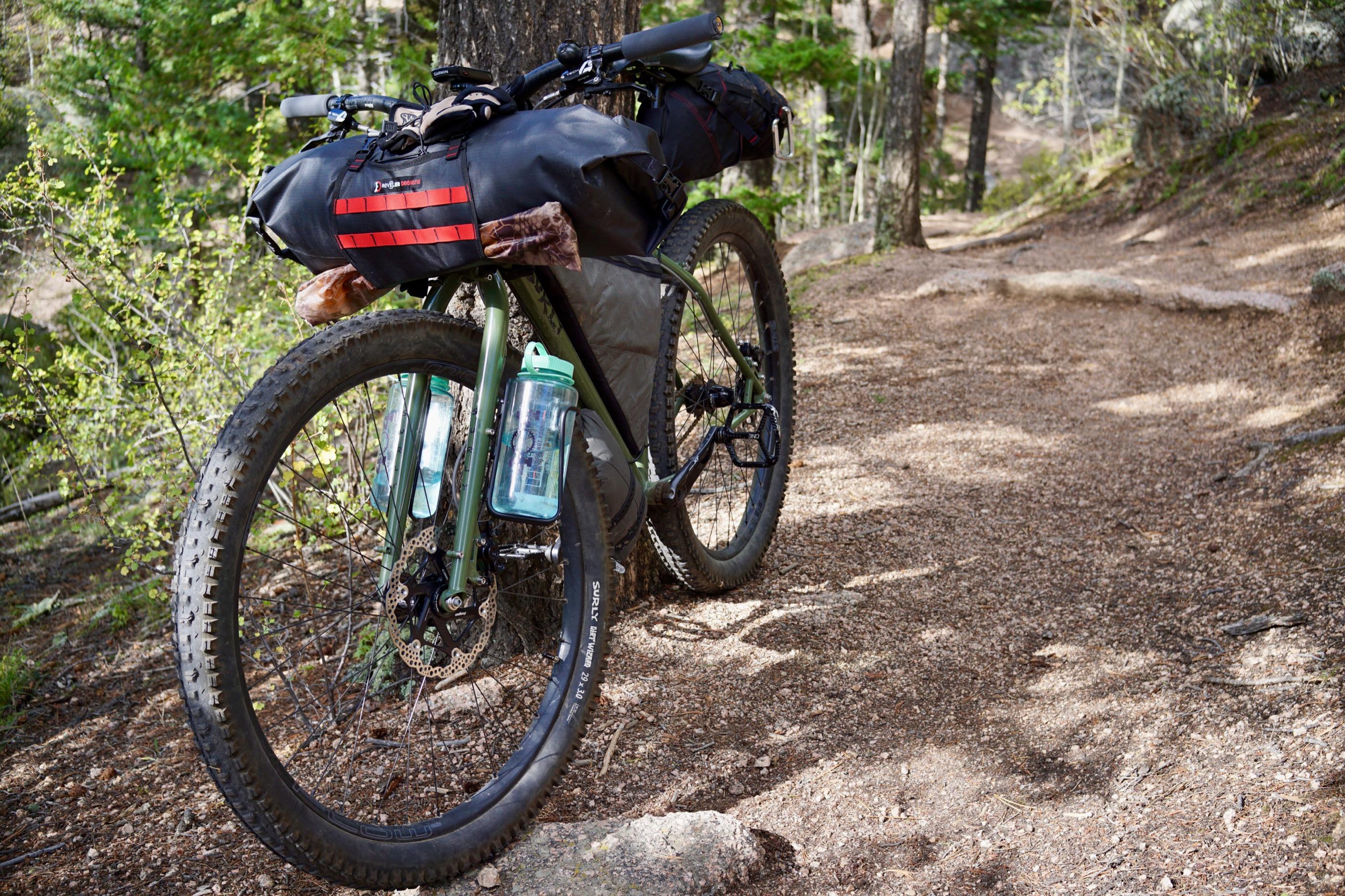 Close view of a Surly Dirt Wizard 29x3.0 tire on the loaded Krampus, frame bag and water bottles visible