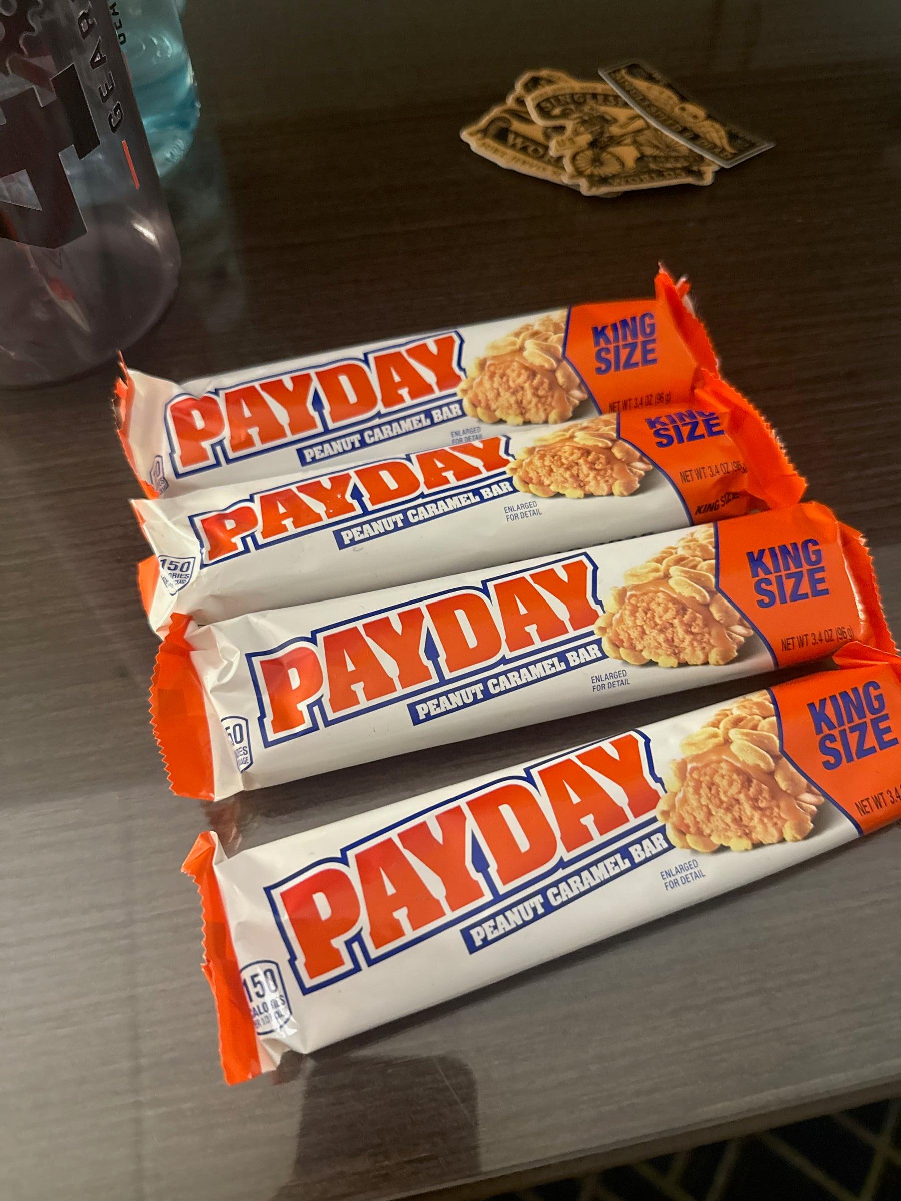 Four King Size Payday peanut caramel bars lined up on a table next to a water bottle and a few Single Speed Worlds stickers