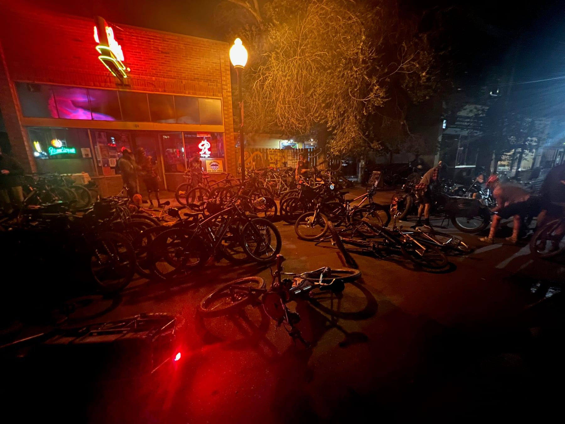 Bikes parked outside a bar with a neon sign at night
