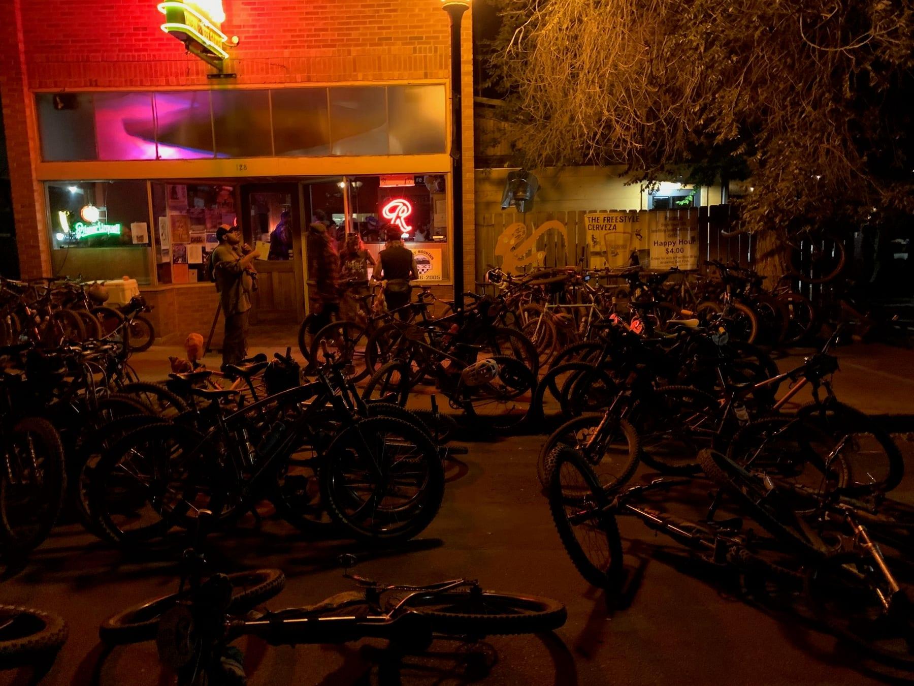 Bikes piled outside a neon-lit bar at night in downtown Salida