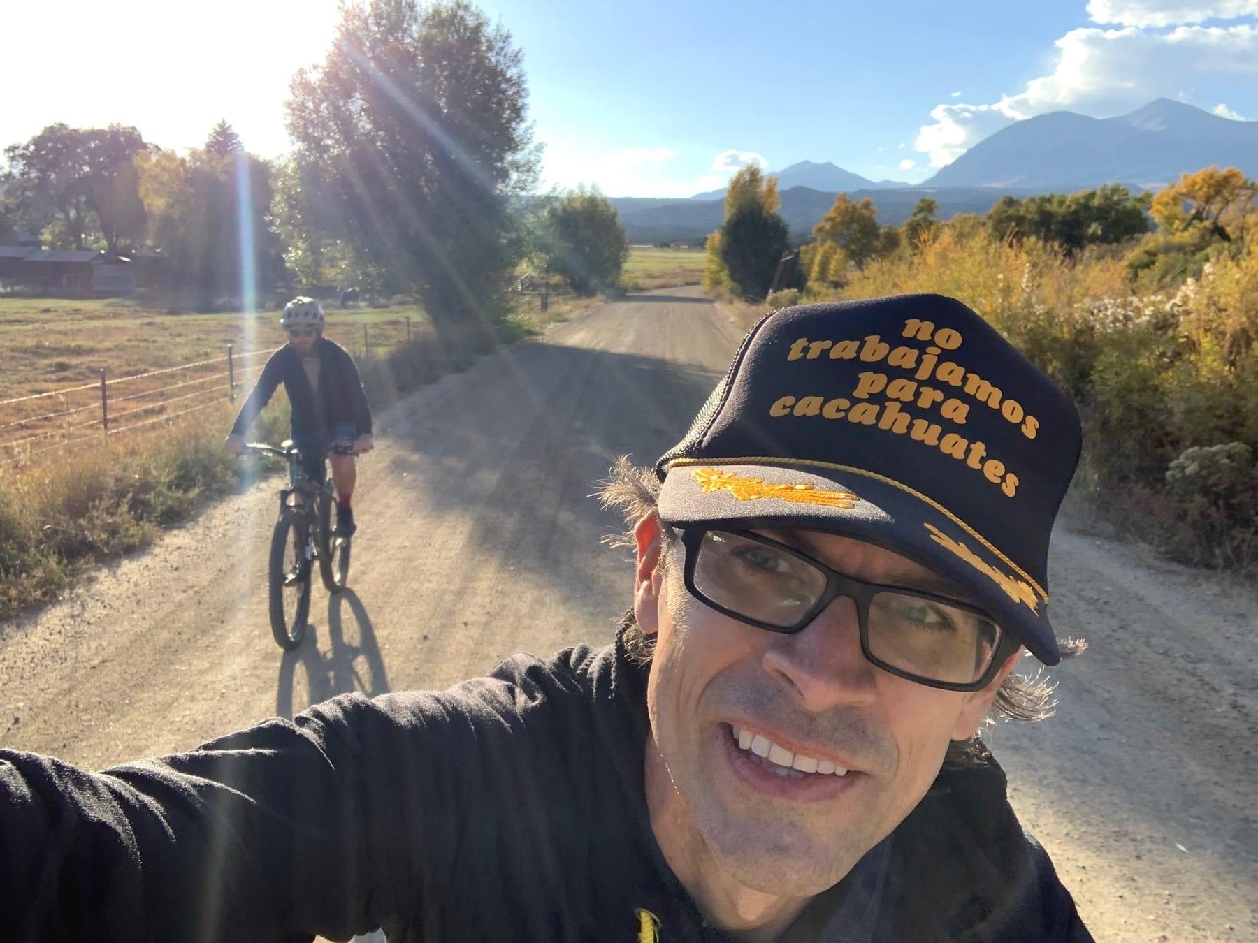 Selfie of a rider climbing a gravel road wearing a knit cap