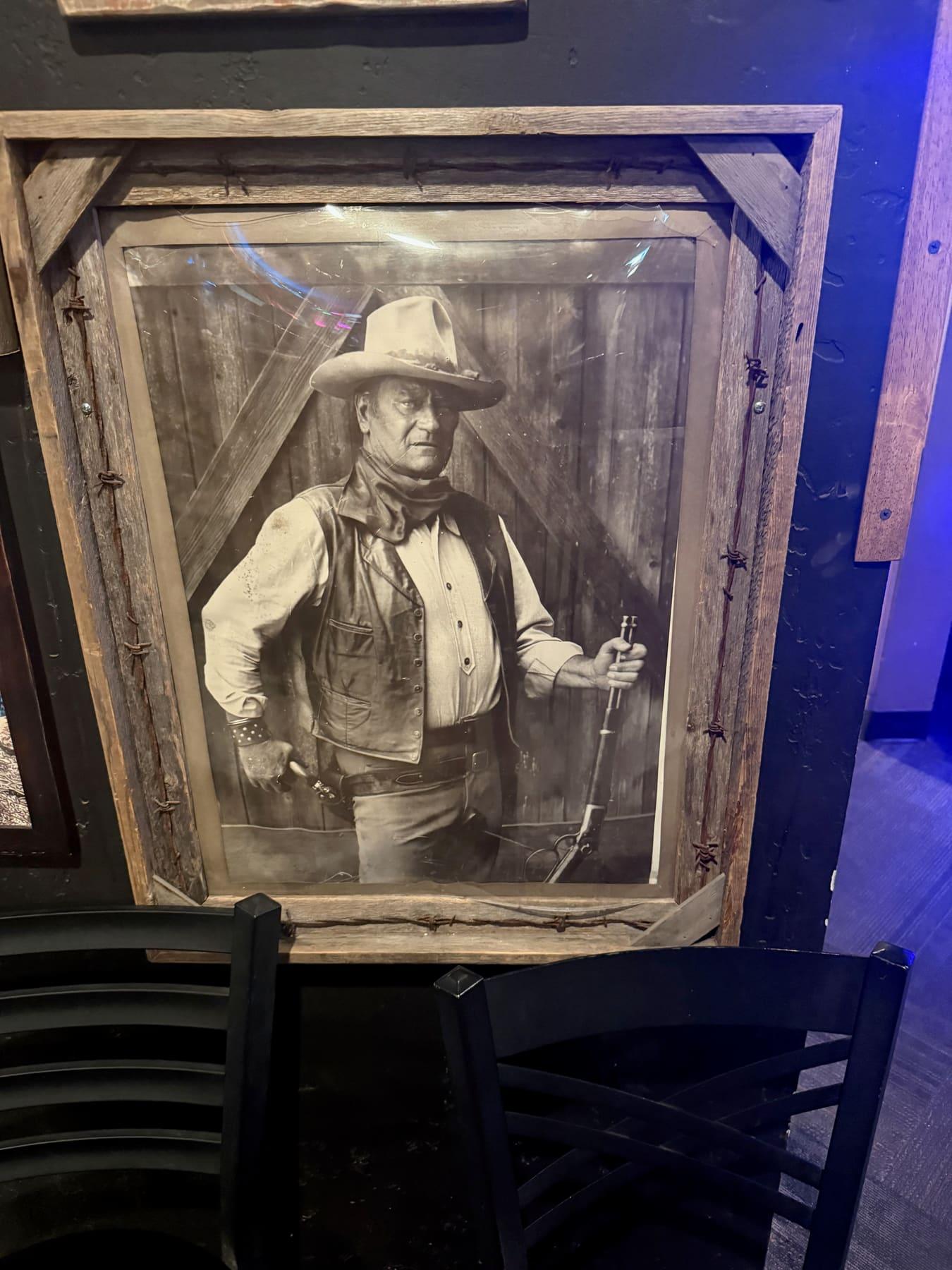 Framed black-and-white photograph of a cowboy holding a rifle, hung on the wall of the Richfield bar