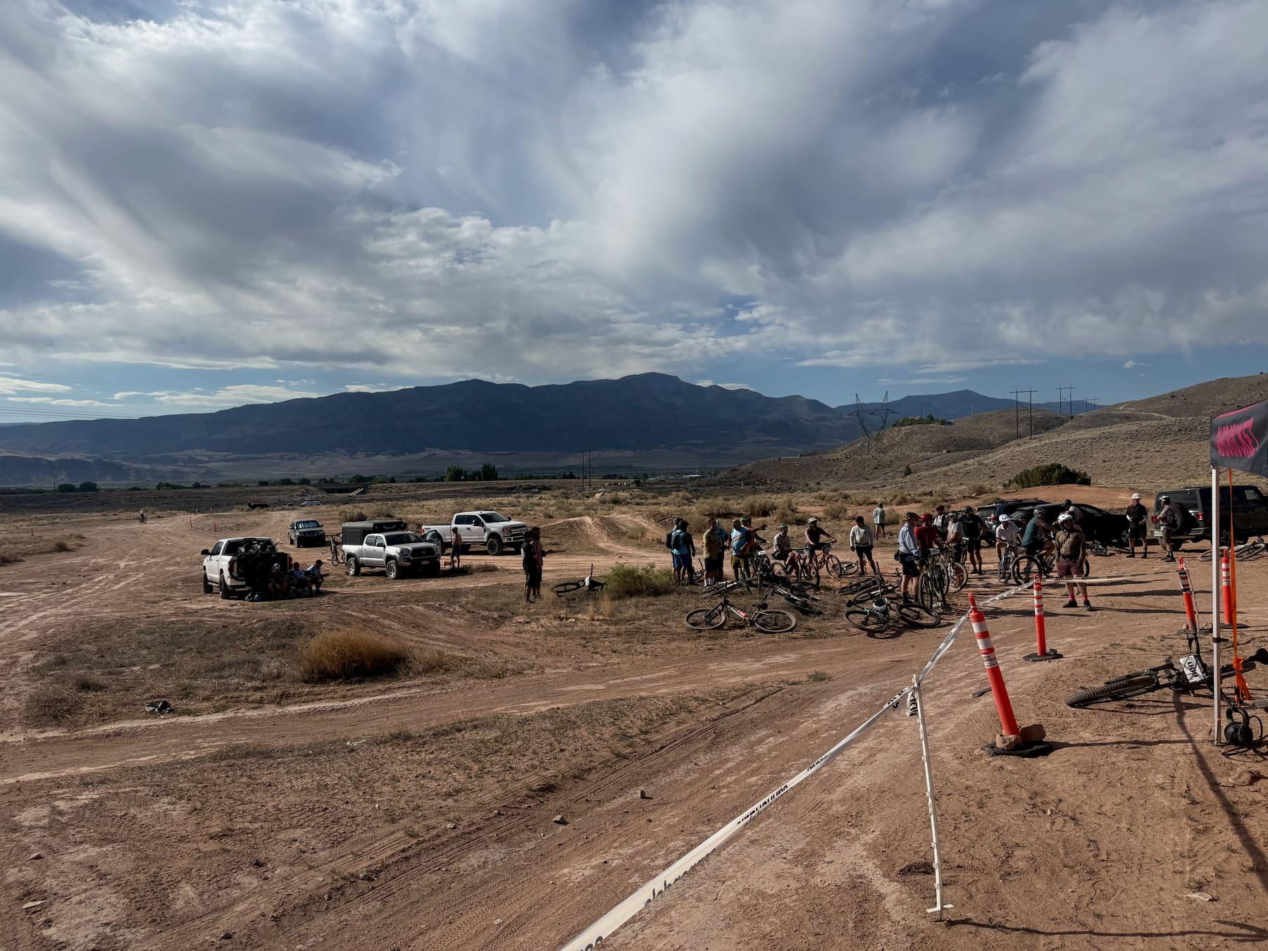 Riders gathering near event tents and orange cones at the Single Speed USA start line in the desert