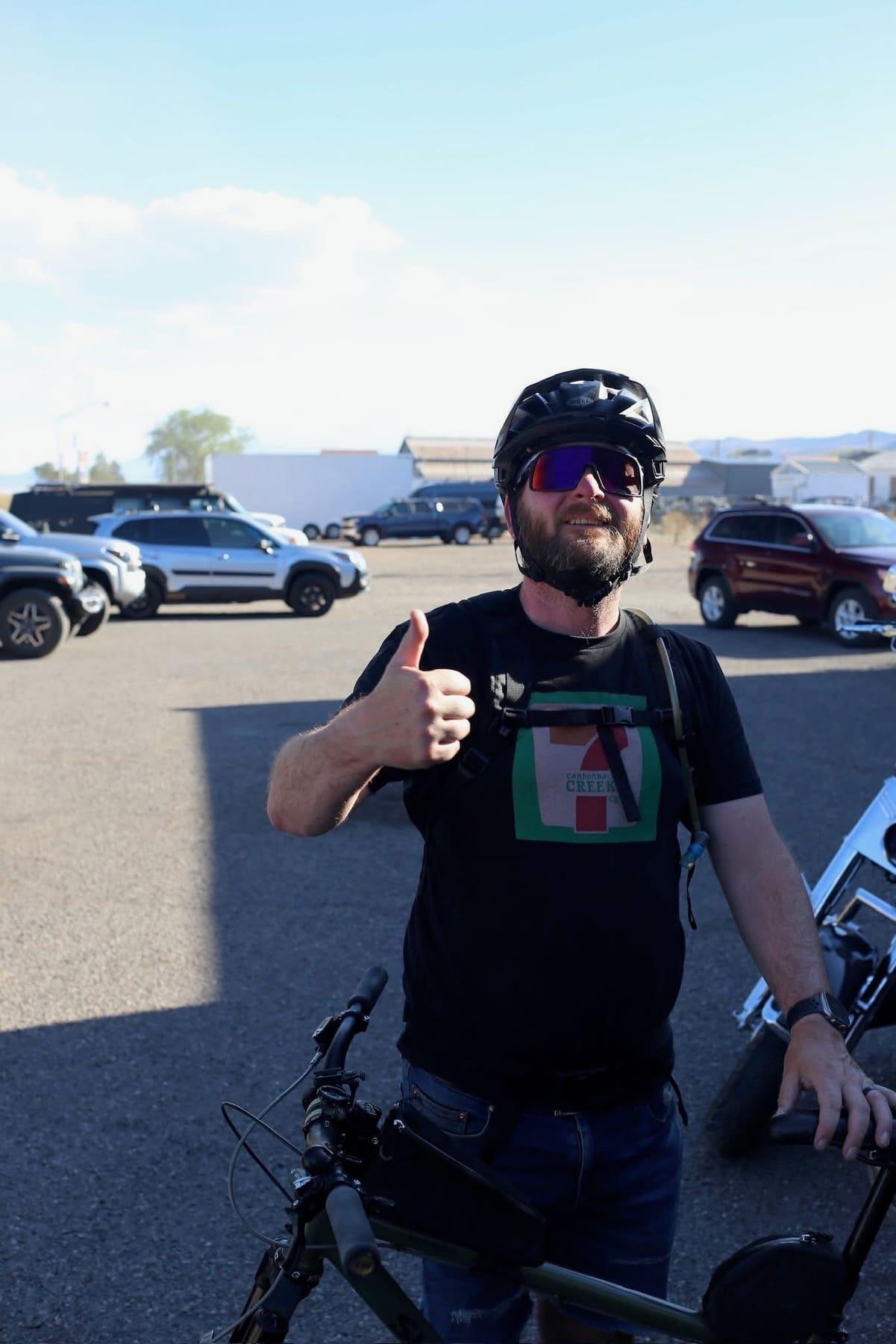 Rider giving a thumbs up next to a parked mountain bike in the Richfield parking lot